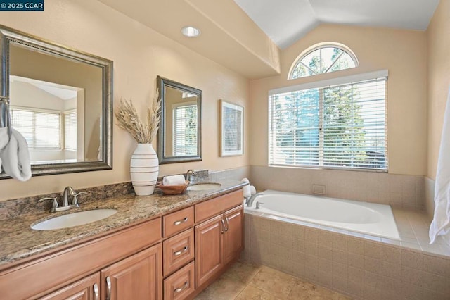 bathroom with tiled bath, vanity, and lofted ceiling