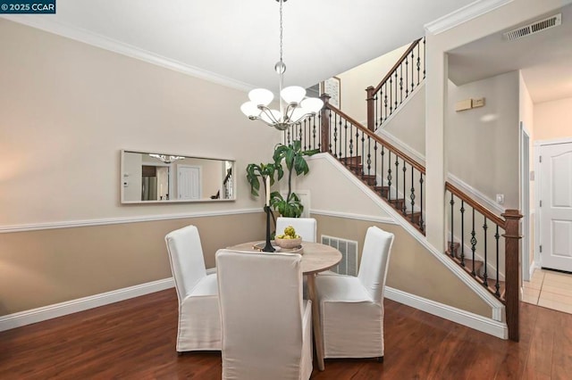 dining room featuring dark hardwood / wood-style floors, crown molding, and a notable chandelier