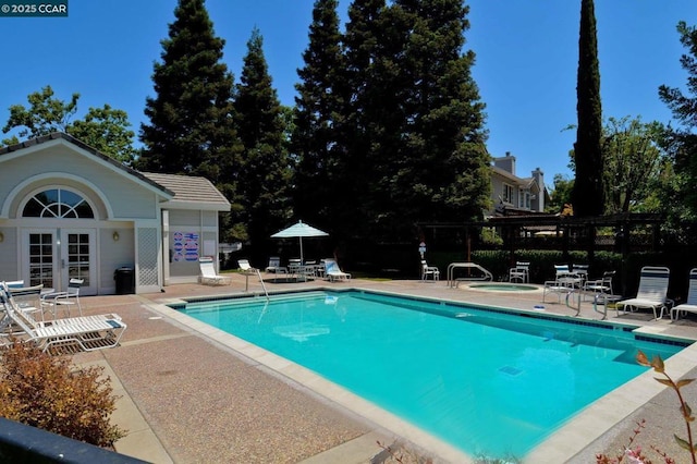 view of swimming pool with an outbuilding, a patio area, and a hot tub