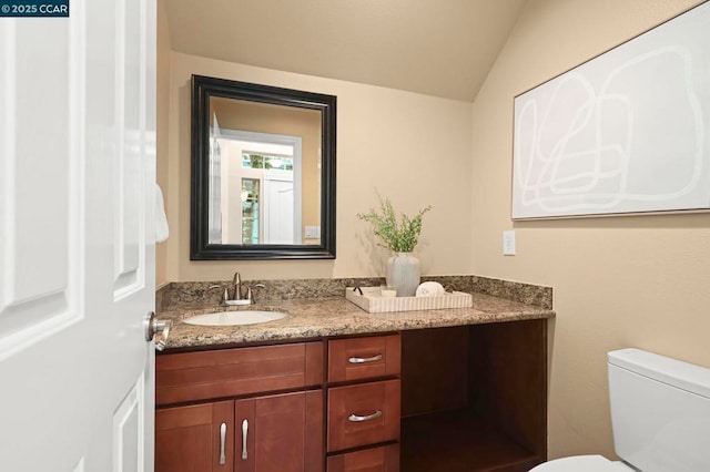 bathroom featuring toilet, vanity, and vaulted ceiling