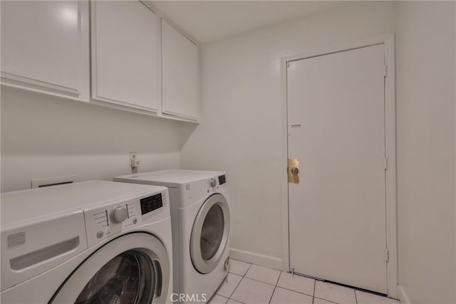 clothes washing area featuring light tile patterned floors, washer and clothes dryer, and cabinets