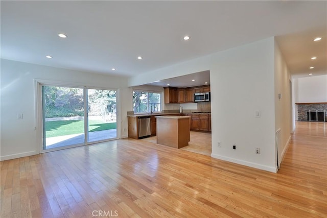 kitchen with stainless steel appliances, a kitchen island, and light hardwood / wood-style flooring