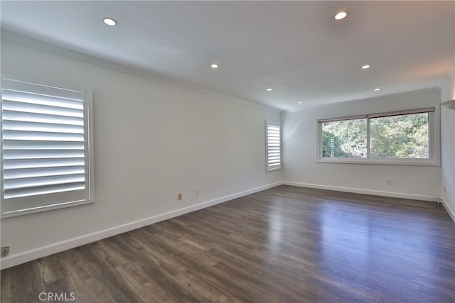 empty room with crown molding, a healthy amount of sunlight, and dark hardwood / wood-style floors