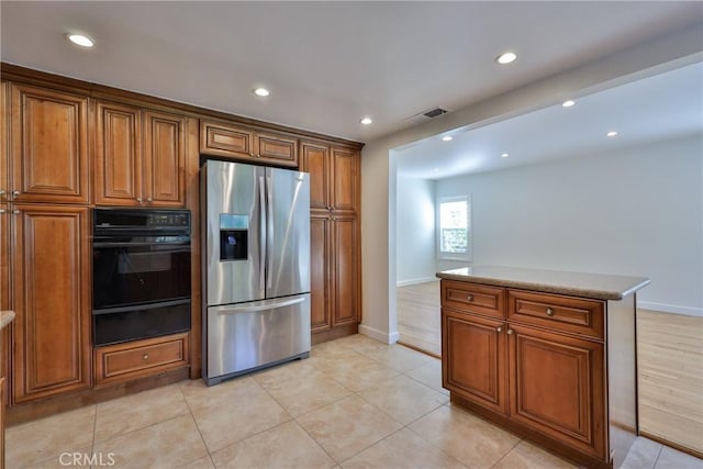 kitchen featuring light tile patterned flooring, black oven, a center island, and stainless steel fridge with ice dispenser