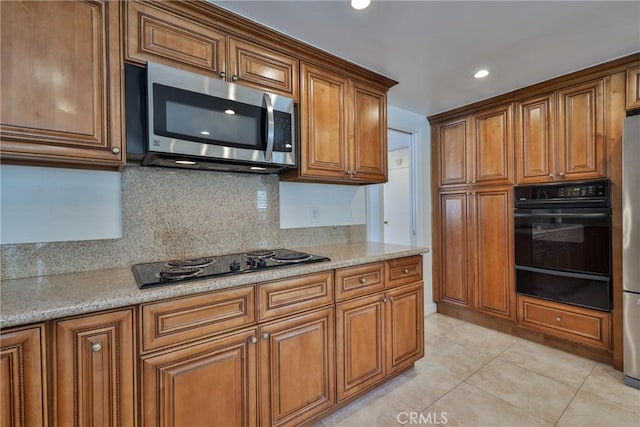 kitchen with light stone countertops, light tile patterned floors, decorative backsplash, and black appliances