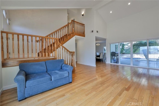 living room featuring a notable chandelier, high vaulted ceiling, beamed ceiling, and light wood-type flooring