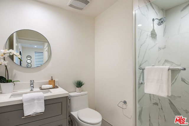 bathroom featuring a shower with door, toilet, and vanity