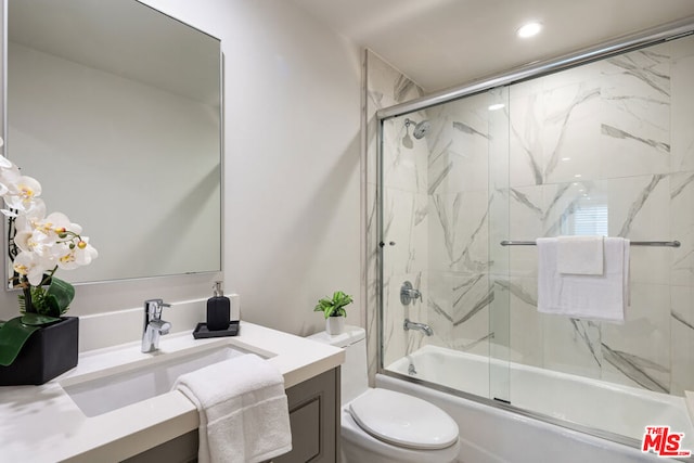 full bathroom with combined bath / shower with glass door, toilet, and vanity