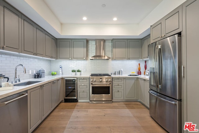 kitchen featuring wine cooler, appliances with stainless steel finishes, decorative backsplash, sink, and wall chimney exhaust hood