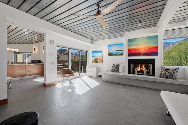 living room with ceiling fan with notable chandelier, a wealth of natural light, and wooden ceiling