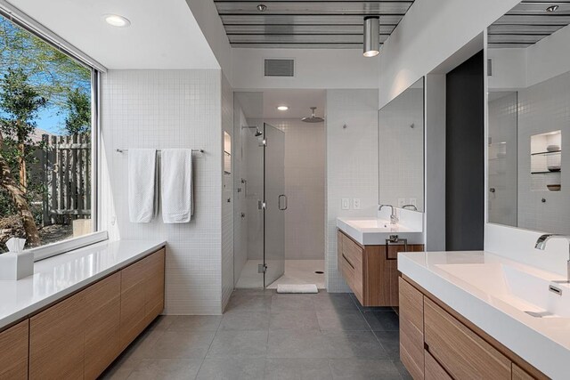 bathroom with vanity, walk in shower, and tile walls