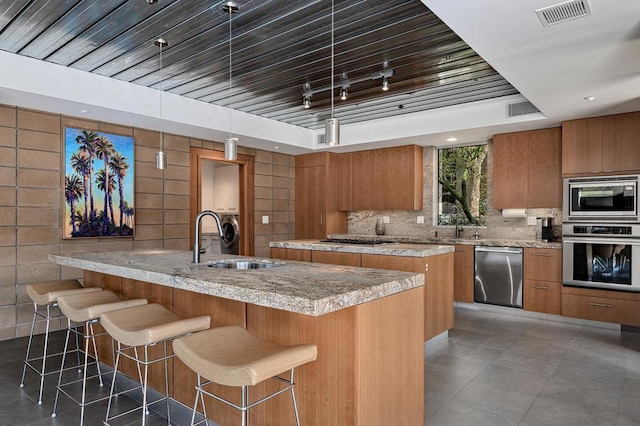 kitchen with sink, a kitchen island, appliances with stainless steel finishes, and decorative light fixtures