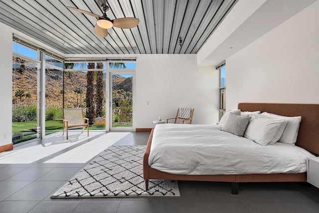 bedroom featuring ceiling fan, multiple windows, expansive windows, and access to outside