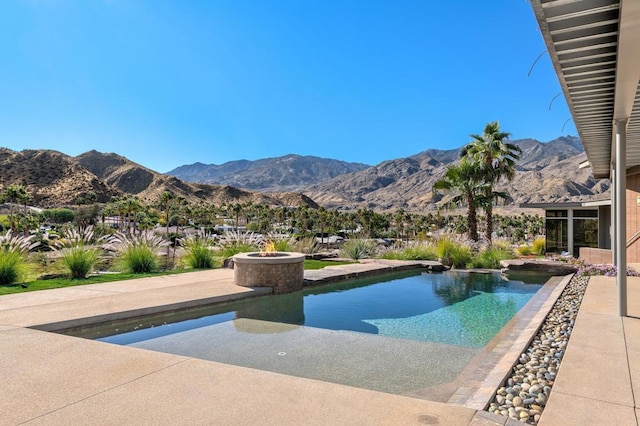 view of pool featuring a mountain view, a patio, and a fire pit