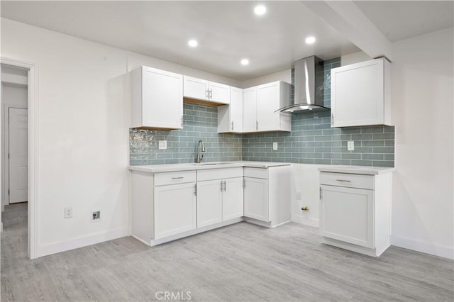 kitchen with sink, white cabinetry, backsplash, and wall chimney exhaust hood