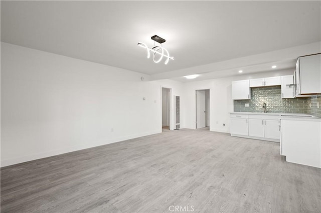 unfurnished living room featuring sink and light hardwood / wood-style floors