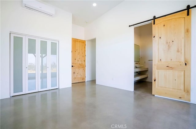 unfurnished room with a high ceiling, a barn door, and a wall unit AC