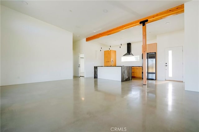 unfurnished living room featuring sink, beam ceiling, and concrete flooring