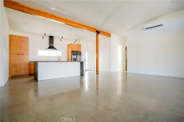 interior space featuring a wall mounted air conditioner, wall chimney range hood, a kitchen island, pendant lighting, and stainless steel fridge