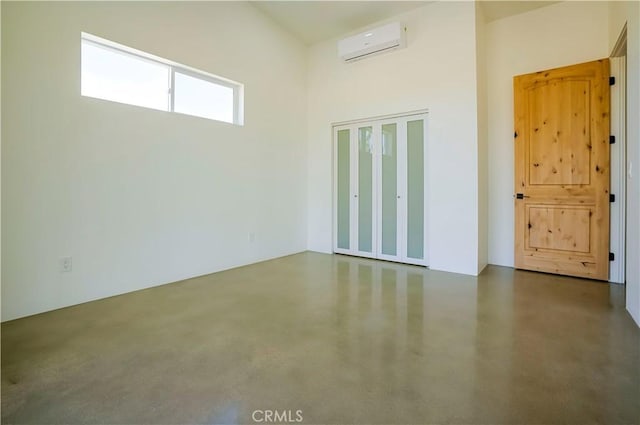 empty room featuring a wall mounted air conditioner and a high ceiling