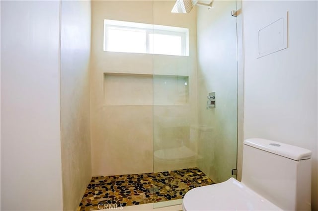 bathroom featuring toilet and a tile shower