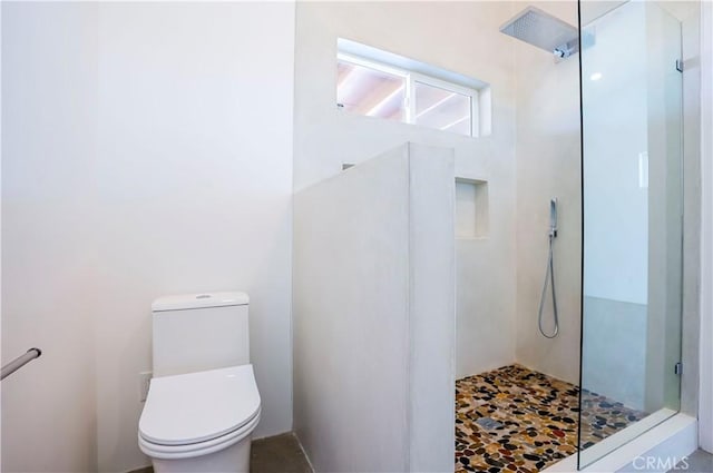 bathroom featuring tiled shower and toilet