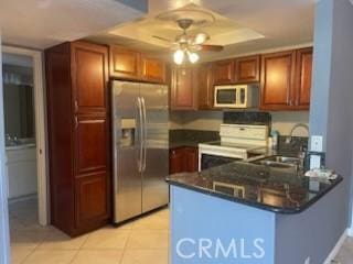 kitchen with a tray ceiling, stainless steel fridge, light tile patterned floors, kitchen peninsula, and electric stove