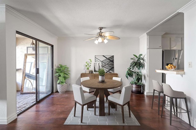 dining room with a textured ceiling, dark wood-style floors, and ornamental molding