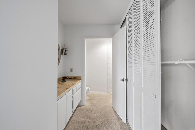 bathroom with vanity, toilet, and a closet