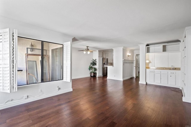 unfurnished living room with dark wood-type flooring, baseboards, and ceiling fan