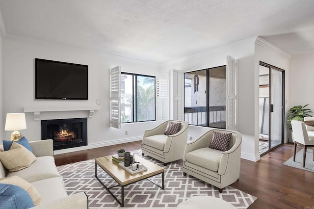 living area featuring baseboards, ornamental molding, a warm lit fireplace, wood finished floors, and a textured ceiling