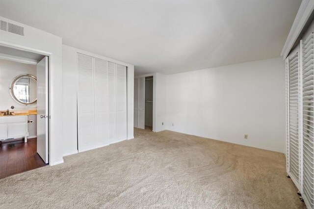 unfurnished bedroom with a sink, visible vents, carpet floors, and connected bathroom