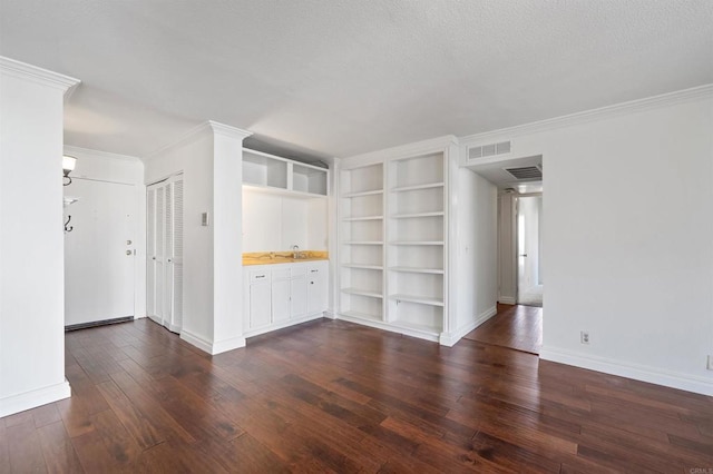 unfurnished living room featuring dark wood-style flooring, built in shelves, and ornamental molding