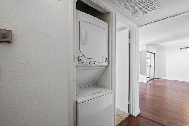 washroom featuring stacked washer and clothes dryer, wood finished floors, and a textured wall