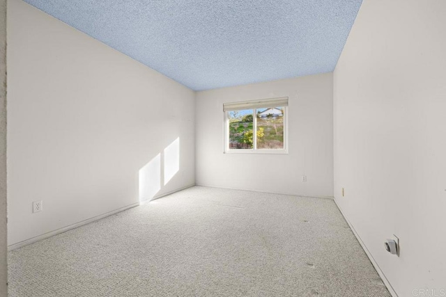 unfurnished room featuring light carpet and a textured ceiling