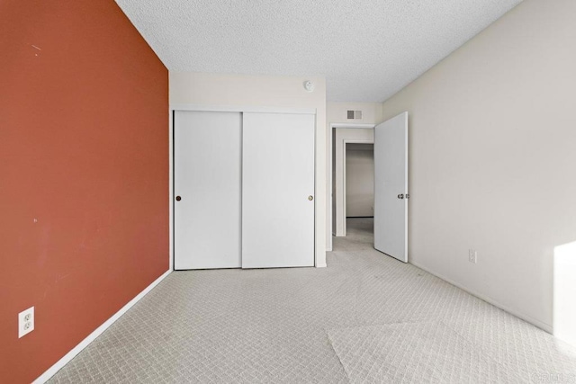 unfurnished bedroom with light carpet, a closet, and a textured ceiling