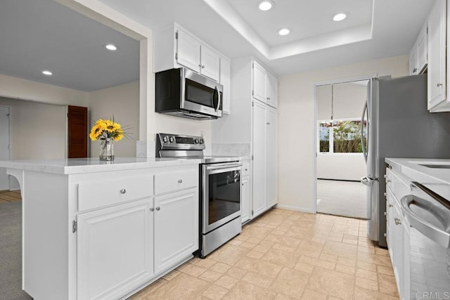 kitchen featuring kitchen peninsula, white cabinets, light colored carpet, a tray ceiling, and stainless steel appliances