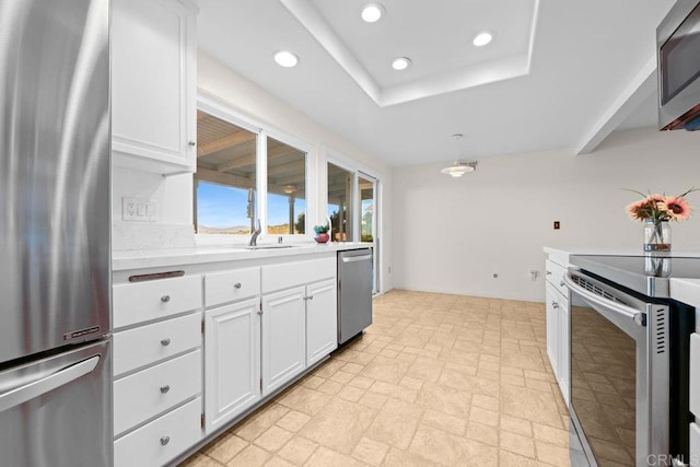 kitchen featuring appliances with stainless steel finishes, decorative light fixtures, and white cabinets