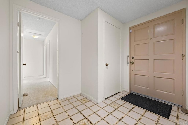 carpeted foyer featuring a textured ceiling