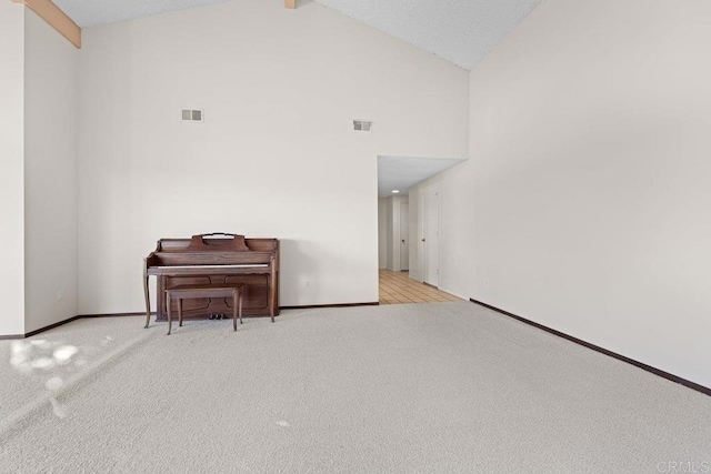 empty room with light colored carpet, beam ceiling, and high vaulted ceiling