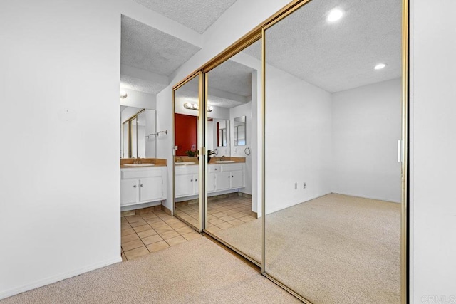 unfurnished bedroom with sink, light colored carpet, a closet, and ensuite bathroom