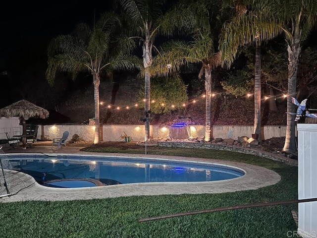 pool at night with an in ground hot tub and a patio