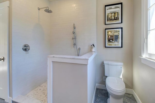 bathroom featuring toilet and a tile shower