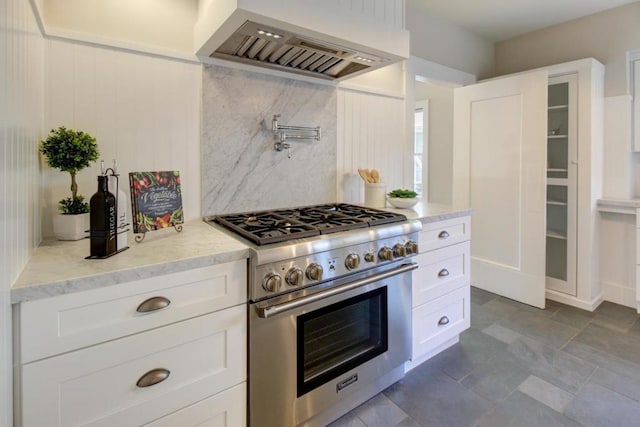 kitchen featuring premium range hood, white cabinetry, backsplash, and high end stove