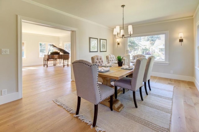 dining room featuring light wood-type flooring, a chandelier, crown molding, and plenty of natural light