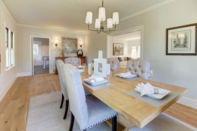 dining space featuring light hardwood / wood-style floors, ornamental molding, and a chandelier