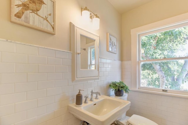 bathroom featuring sink, tile walls, and toilet