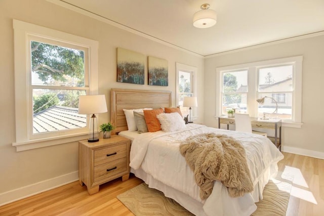 bedroom featuring crown molding, light wood-type flooring, and multiple windows