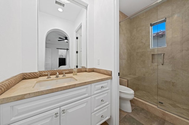 bathroom featuring toilet, a shower with shower door, ceiling fan, and vanity