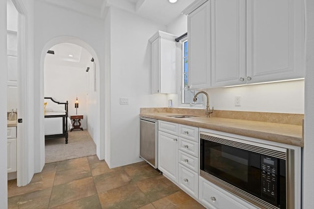 kitchen with sink, black microwave, white cabinetry, and stainless steel dishwasher